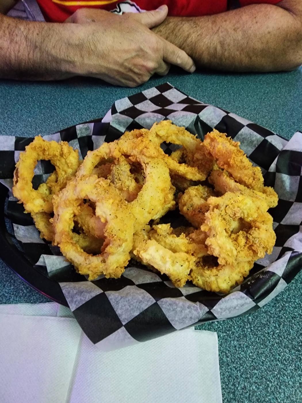 A basket of golden onion rings on checked paper